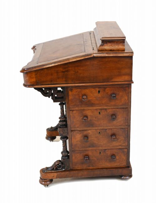 fig 1. A Victorian walnut Davenport desk featuring a sloping leather writing surface, a raised top compartment, and carved column supports.
