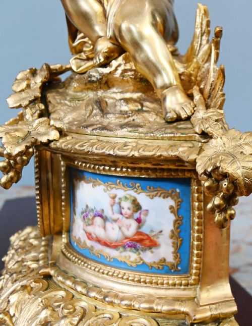 fig 2. A late 19th-century French Rococo gilt bronze mantel clock featuring a sculpted cherub playing a pipe atop, flanked by sky-blue painted porcelain plaques.