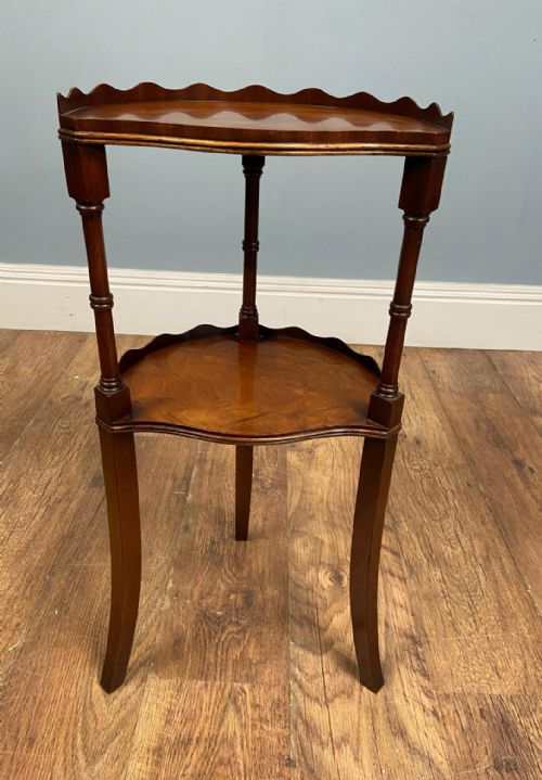 fig 1. An Edwardian walnut two-tier side table featuring a scalloped top rim, turned upper leg supports, and curved lower legs.