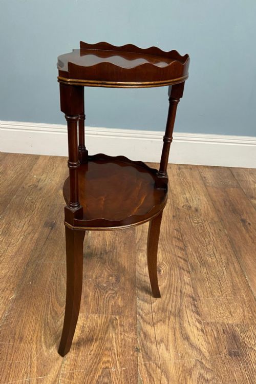 fig 2. An Edwardian walnut two-tier side table featuring a scalloped top rim, turned upper leg supports, and curved lower legs.