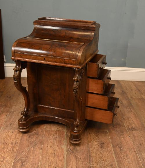 fig 1. A Victorian walnut Davenport desk featuring a sloped piano-style lid, carved cabriole supports, and a rich wood grain finish.