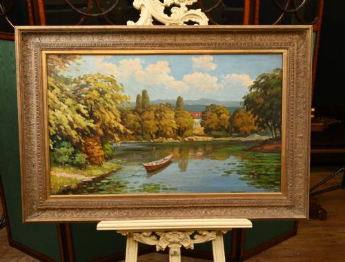 fig 1. A framed French impressionist oil painting depicting a river scene with a wooden boat moored near tree-lined banks under a blue sky.