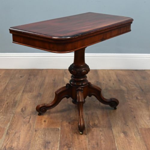 fig 1. A Victorian mahogany fold-over card table with a rectangular top supported by a central carved pedestal and four scroll-cut legs on castors.