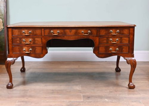 fig 1. Late Victorian mahogany writing desk featuring a tan gilt-tooled leather inset top, brass swan-neck handles, and carved cabriole legs with ball-and-claw feet.