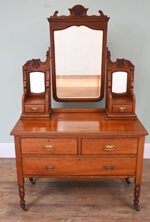 fig 1. An Edwardian mahogany dressing table featuring a central swinging mirror flanked by two trinket drawers, set above a chest with three drawers and brass drop handles.