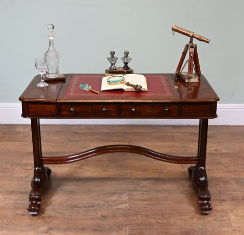 fig 2. A late Victorian mahogany writing table featuring a central red leather skiver with gold tooling, two frieze drawers, turned end supports, and a curved stretcher.