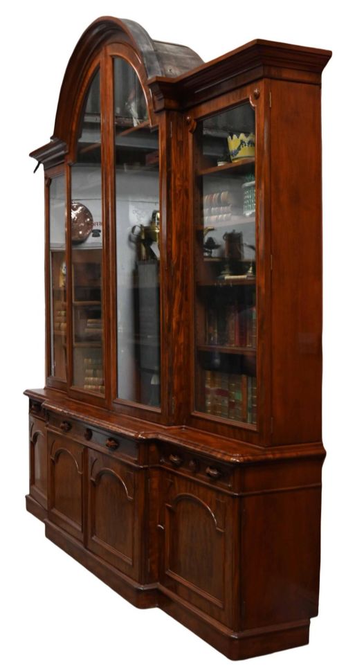 fig 2. A large Victorian mahogany breakfront library bookcase featuring an arched central section with glazed upper doors over solid panelled cupboards.