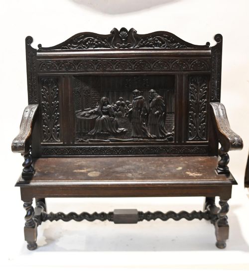 fig 2. A late 19th-century dark carved walnut hall bench featuring a pictorial relief back panel, scrolled armrests, and turned stretchers.