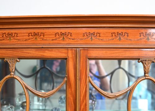 fig 1. An Edwardian Sheraton Revival display cabinet in painted satinwood with glazed double doors, decorative oval glazing bars, and lower cupboard doors on slender square legs.