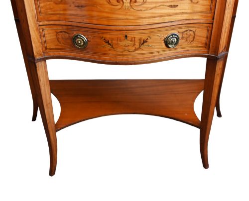fig 2. An Edwardian satinwood glazed display cabinet featuring classical urn marquetry, a swan-neck pediment, bowed glass sides, and drawers over tapered legs.