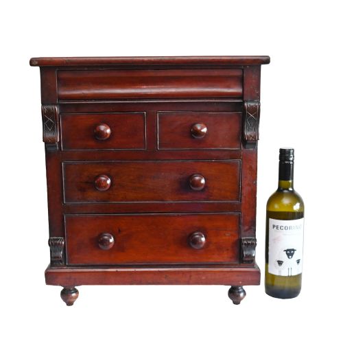 fig 1. A 19th-century Scottish mahogany miniature apprentice chest featuring two short over two long drawers, a top cushion drawer, turned knobs, carved corbels, and turned feet.