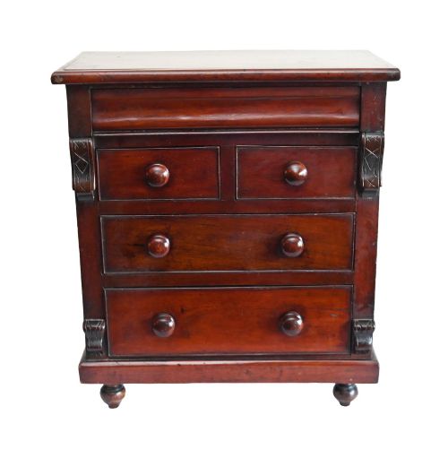 fig 2. A 19th-century Scottish mahogany miniature apprentice chest featuring two short over two long drawers, a top cushion drawer, turned knobs, carved corbels, and turned feet.