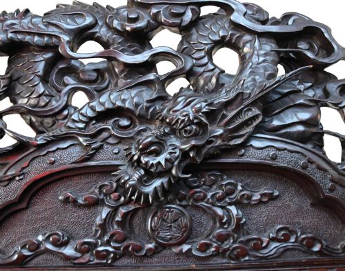 fig 2. An intricately carved dark hardwood Japanese Meiji display cabinet featuring a dragon pediment, glazed door, and tiered asymmetrical shelves.
