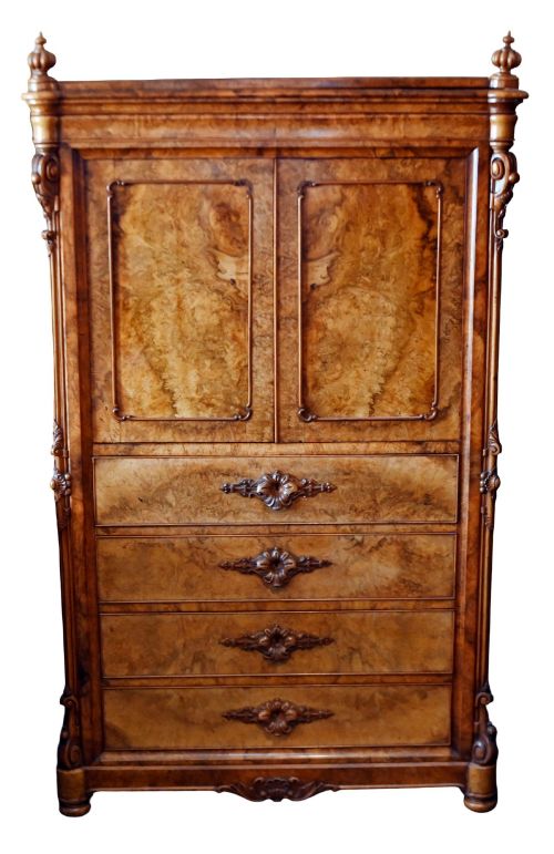 fig 1. A tall 19th-century French Louis Philippe secretaire desk featuring figured birds-eye maple veneer, carved wooden handles, upper cabinet doors, and finials on top.