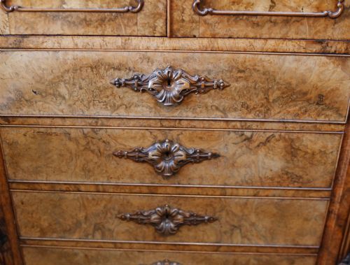 fig 2. A tall 19th-century French Louis Philippe secretaire desk featuring figured birds-eye maple veneer, carved wooden handles, upper cabinet doors, and finials on top.