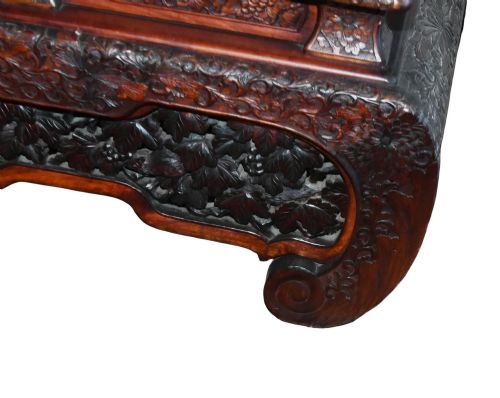 fig 1. An intricately carved dark brown Japanese Meiji period display cabinet featuring asymmetrical open shelves, relief-carved cupboard doors, and a decorative cresting piece.