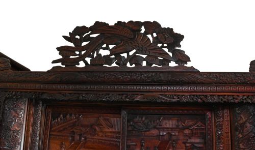 fig 3. An intricately carved dark brown Japanese Meiji period display cabinet featuring asymmetrical open shelves, relief-carved cupboard doors, and a decorative cresting piece.