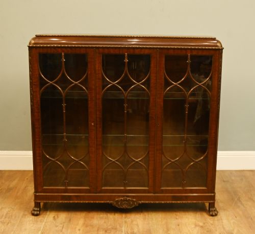 fig 1. A Chippendale Revival mahogany display cabinet featuring three astragal glazed doors and carved ball and claw feet.