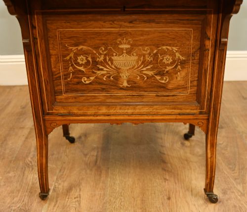 fig 2. An Edwardian mahogany Davenport desk with urn marquetry inlays, a leather writing slope, brass gallery rim, and legs on castors.