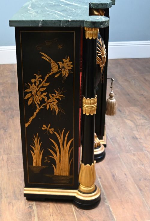 fig 2. A Regency Revival side cabinet featuring a green marble top, a central black lacquer door decorated with gilded Chinoiserie artwork, and flanking open shelves with red interiors.