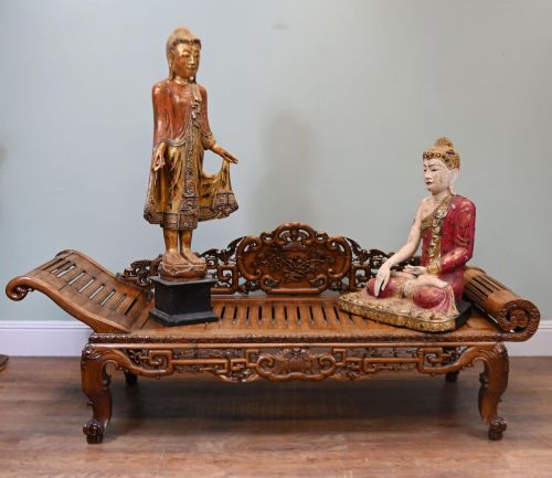 fig 1. An intricately hand-carved warm brown hardwood Chinese opium bench featuring a slatted seat, elevated recline end, and pierced scrollwork along the backrest.