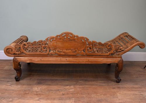 fig 3. An intricately hand-carved warm brown hardwood Chinese opium bench featuring a slatted seat, elevated recline end, and pierced scrollwork along the backrest.