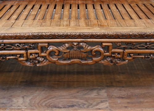 fig 5. An intricately hand-carved warm brown hardwood Chinese opium bench featuring a slatted seat, elevated recline end, and pierced scrollwork along the backrest.