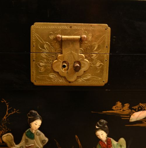 fig 3. A black lacquered rectangular wooden chest embellished with raised soapstone figures and landscape scenes, fitted with an etched brass lock plate.