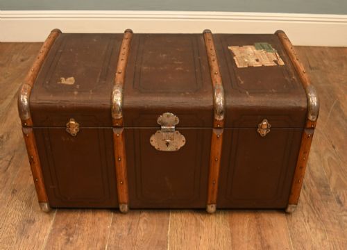 fig 1. A dark brown 1920s antique steamer trunk with wooden slats, corner brackets, and a central metal latch.