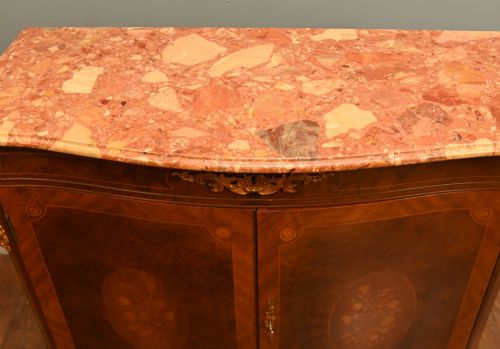 fig 1. A Louis XV Revival walnut side cabinet featuring a serpentine front, floral marquetry inlay, pink marble top, and gilt-bronze mounts on cabriole legs.