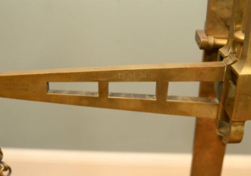 fig 2. A nineteenth-century brass Avery balance scale featuring a tall central pillar, horizontal beam, twin hanging circular pans, and nested counterweights.