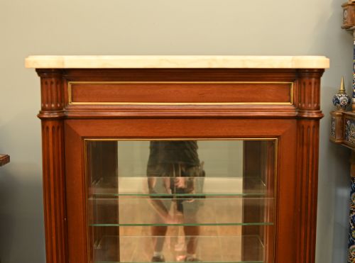 fig 2. A French Directoire style mahogany vitrine cabinet featuring a single glazed door, fluted corner pilasters, brass line inlays, tapered turned feet, and a marble top surface.
