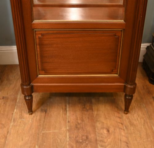 fig 3. A French Directoire style mahogany vitrine cabinet featuring a single glazed door, fluted corner pilasters, brass line inlays, tapered turned feet, and a marble top surface.