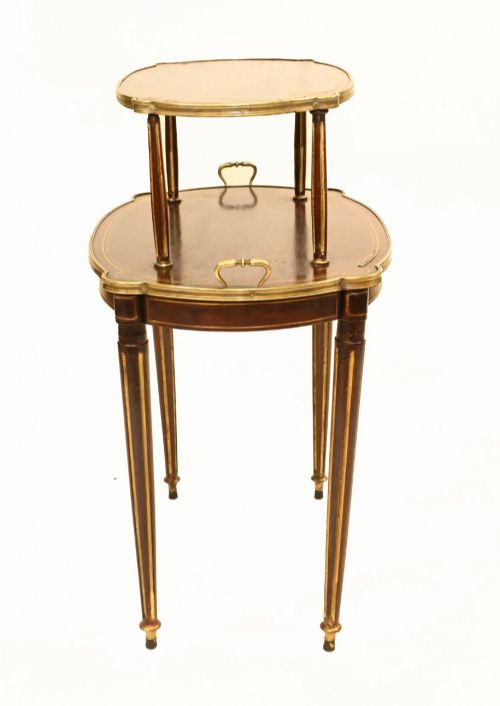 fig 1. A two-tiered mahogany side table featuring shaped oval tops edged with brass galleries, slender turned legs, and brass side handles on the lower tier.