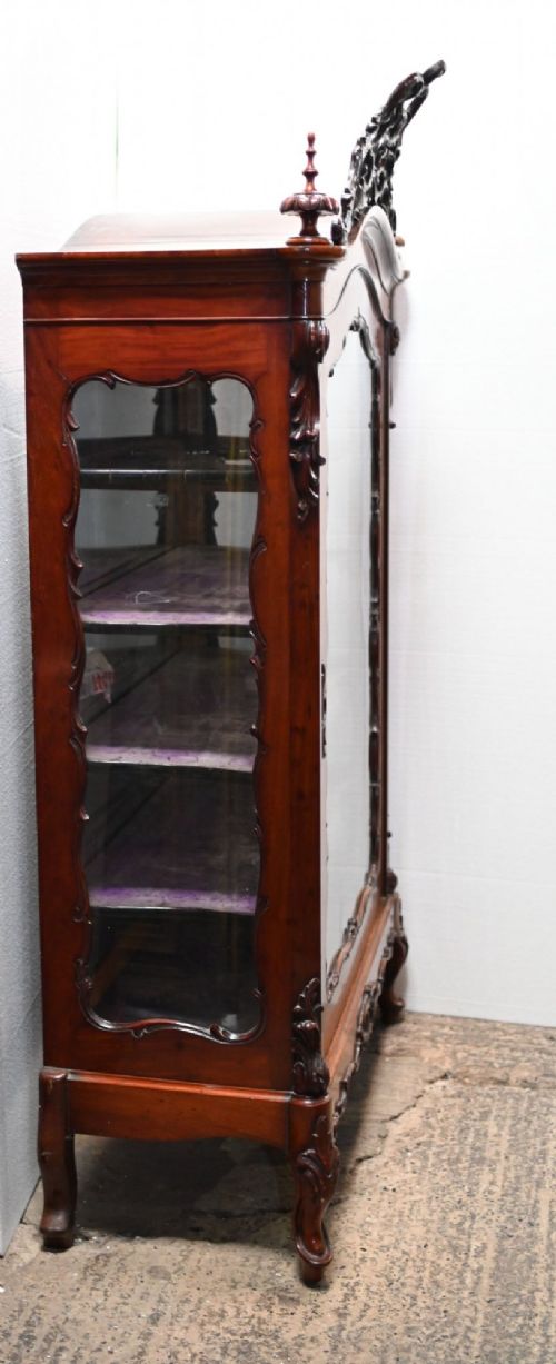 fig 1. An antique French mahogany glazed vitrine cabinet featuring ornate cresting carvings, glass shelves, and carved cabriole legs.