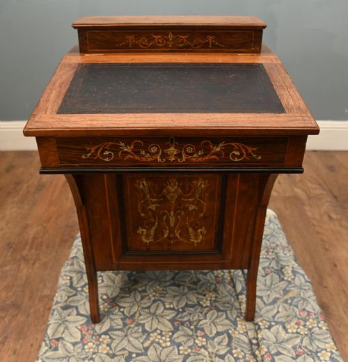 fig 2. A late Victorian Sheraton Revival davenport desk crafted from warm brown wood, featuring decorative marquetry inlay and a dark leather inset writing surface.