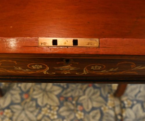 fig 3. A late Victorian Sheraton Revival davenport desk crafted from warm brown wood, featuring decorative marquetry inlay and a dark leather inset writing surface.