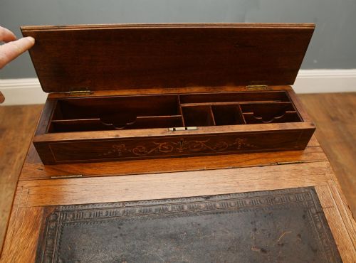 fig 5. A late Victorian Sheraton Revival davenport desk crafted from warm brown wood, featuring decorative marquetry inlay and a dark leather inset writing surface.
