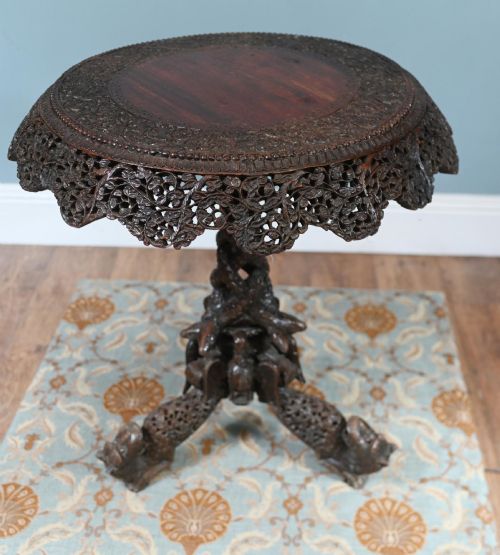 fig 2. An antique dark hardwood Burmese side table with intricate pierced foliage carving around the circular top and a carved tripod base featuring mythological figure feet.