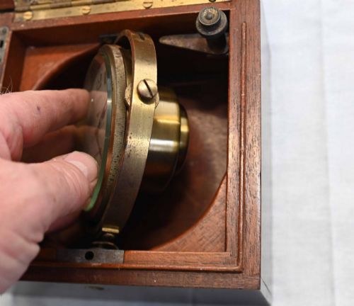 fig 2. A 1920s Longines marine chronometer clock with a white dial set in a brass gimbal mechanism inside an open mahogany box.
