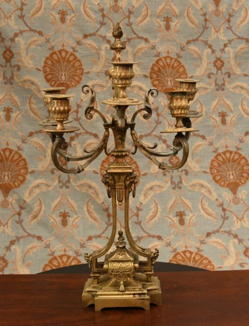 fig 1. A 19th-century Louis XVI style gilt bronze clock garniture set comprising a central ornate mantel clock flanked by two matching five-light candelabras.