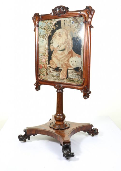 fig 1. A Victorian carved mahogany fire screen featuring a needlepoint tapestry panel depicting a large hound and a small terrier inside a wooden kennel.