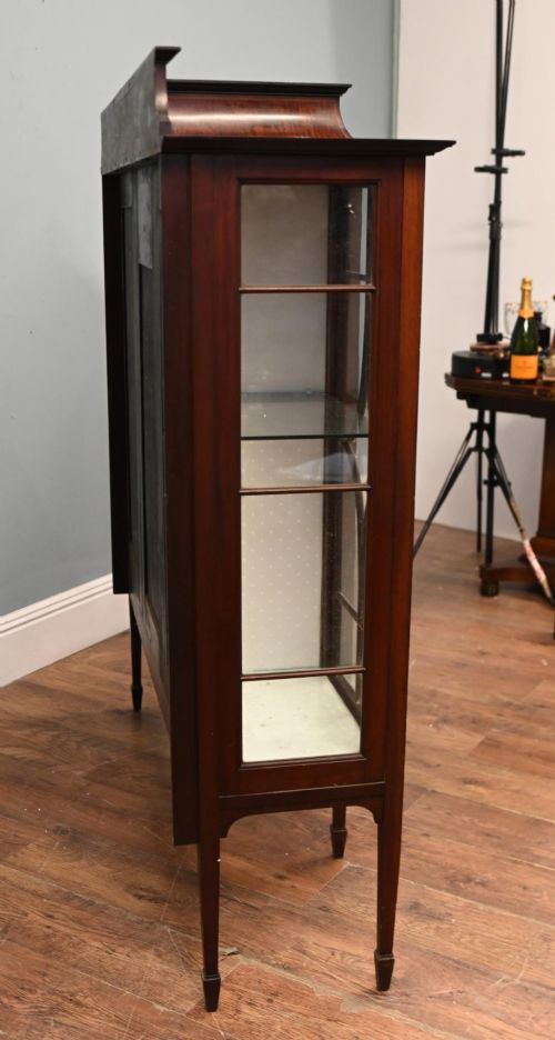 fig 2. An Edwardian inlaid mahogany display cabinet featuring astragal glazed side doors, a central wooden cupboard with oval marquetry, and slender square tapered legs.