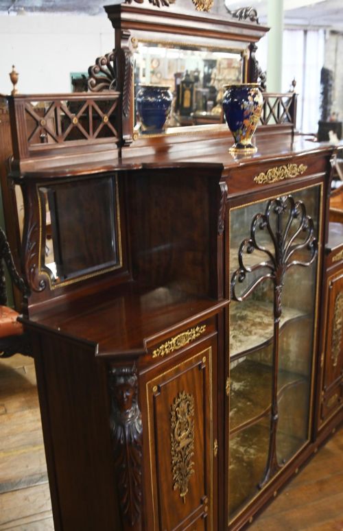 fig 2. A dark mahogany display cabinet featuring gilt ormolu mounts, bevelled mirror panels, and a central glass door with decorative organic glazing bars.