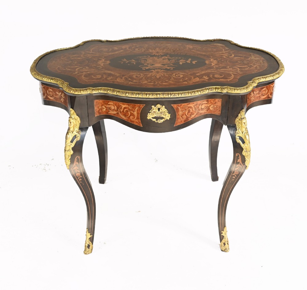 A 19th-century French Louis XV style centre table featuring a serpentine-edged top decorated with floral marquetry inlay, gilt-brass rim mounts, cabriole legs, and a single drawer.