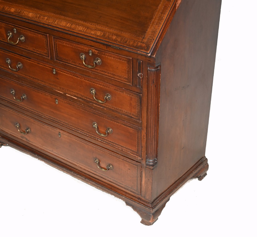 A late 18th-century mahogany bureau bookcase featuring upper astragal glazed double doors with an oval shell marquetry pediment, above a slanted fall-front writing desk and four graduating drawers with brass handles. View IV