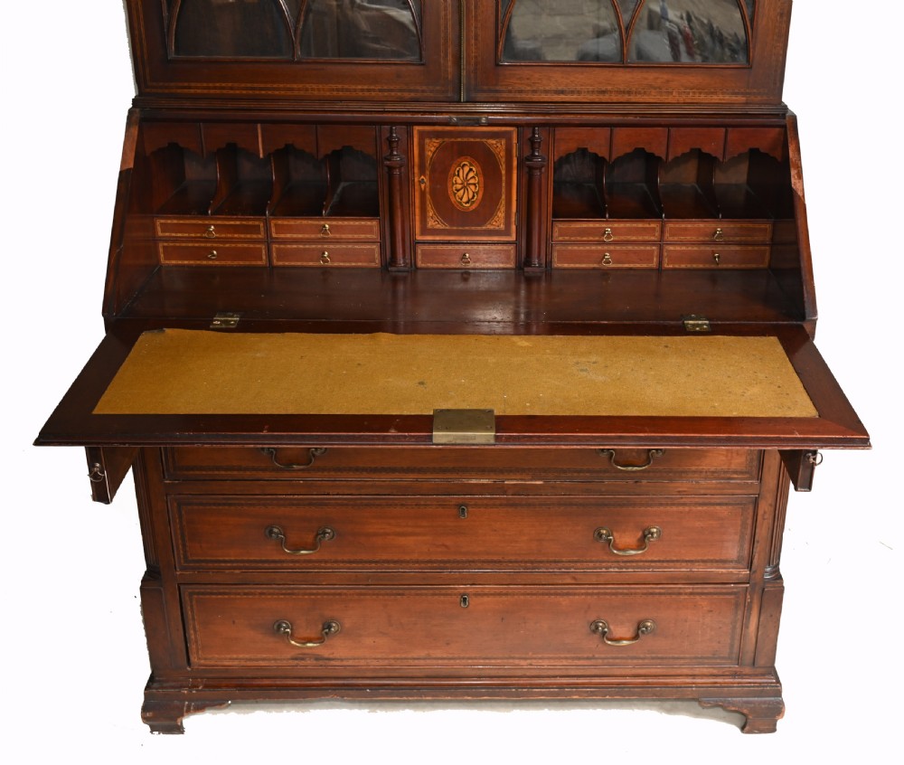 A late 18th-century mahogany bureau bookcase featuring upper astragal glazed double doors with an oval shell marquetry pediment, above a slanted fall-front writing desk and four graduating drawers with brass handles. View VI