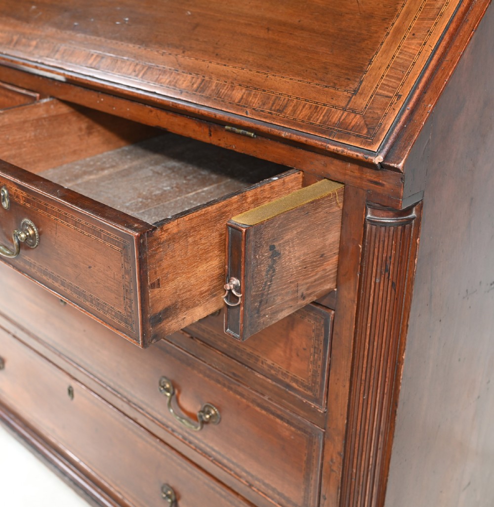 A late 18th-century mahogany bureau bookcase featuring upper astragal glazed double doors with an oval shell marquetry pediment, above a slanted fall-front writing desk and four graduating drawers with brass handles. View VIII