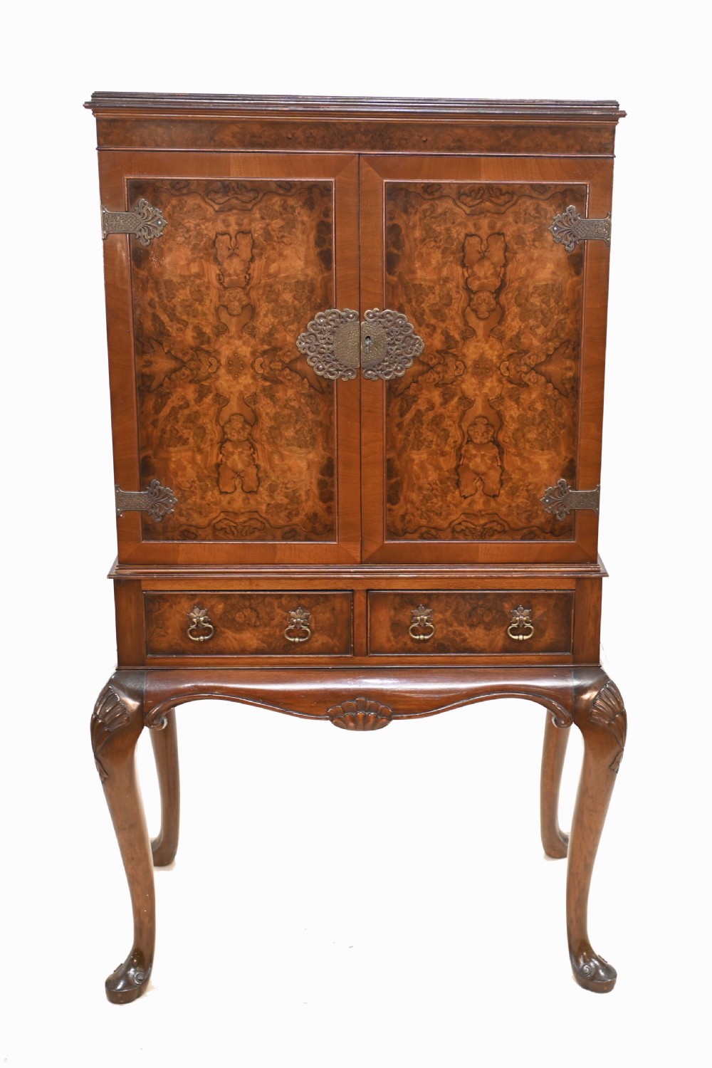 An Art Deco burr walnut drinks cabinet on a carved cabriole leg stand with ornate brass hardware and two lower drawers.