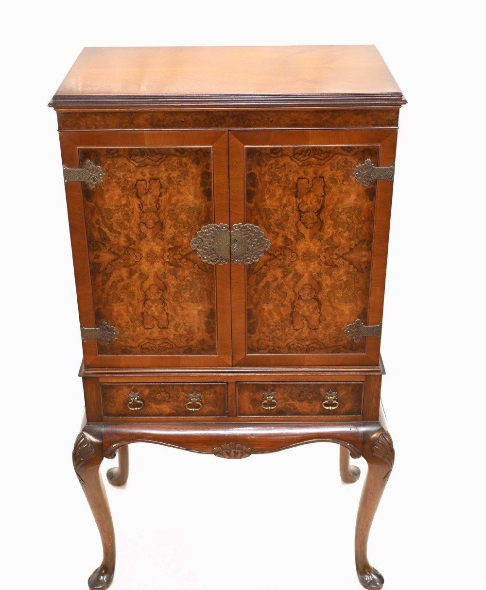An Art Deco burr walnut drinks cabinet on a carved cabriole leg stand with ornate brass hardware and two lower drawers. View IV
